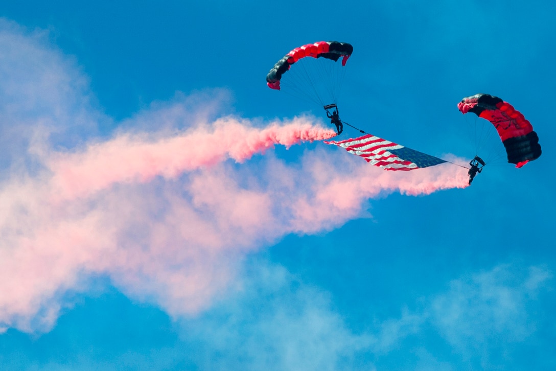 Army paratroopers descend through the sky with the American flag during the opening ceremony of the South Carolina National Guard Air and Ground Expo at McEntire Joint National Guard Base, S.C., May 6, 2017. The paratroopers are assigned to the Black Daggers, the official U.S. Army Special Operations Command Parachute Demonstration Team. The expo showcases South Carolina National Guard airmen and soldiers. Army National Guard photo by Sgt. Brian Calhoun