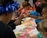 Staff Sgt. Rachael Walker, an aerospace ground equipment craftsman assigned to the 28th Maintenance Squadron, helps children make luau lei necklaces at the Child Development Center on Ellsworth Air Force Base, S.D., May 10, 2017. May is Asian Pacific Islander American Heritage Month, a month dedicated to commemorating the immigration of the first Japanese citizens to the United States. (U.S. Air Force photo by Airman Nicolas Z. Erwin)