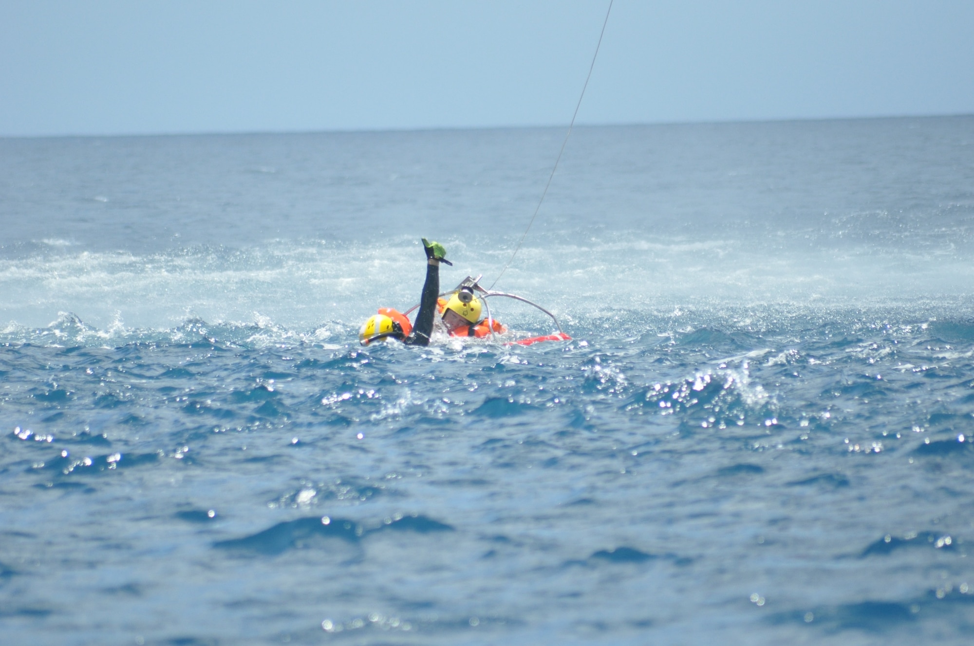 The U.S. Coast Guard diver signals the chopper to lift a member of the 53rd Weather Reconnaissance Squadron during joint training between the 53rd WRS and the U.S. Coast Guard, based out of Puerto Rico, in the water survival portion of Survival, Evasion, Resistance, and Escape (SERE) refresher training in the coastal waters of St. Croix, U.S. Virgin Islands, May 8,2017. (U.S. Air Force photo//Master Sgt. Jessica Kendziorek)