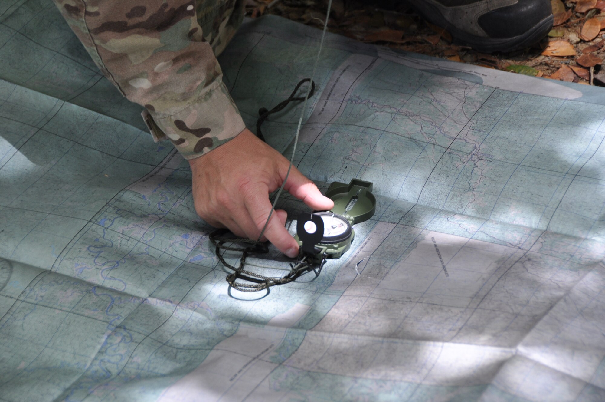 Tech. Sgt. Nathan Martinez, 302nd Operations Group SERE specialist, shows the members of the 53rd Weather Reconnaissance Squadron how to find truth north using a compass and map during the land survival portion of Survival, Evasion, Resistance, and Escape (SERE) refresher training in the woods of St. Croix, U.S. Virgin Islands, May 9,2017. (U.S. Air Force photo//Master Sgt. Jessica Kendziorek)
