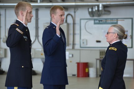 Brig. Gen. Lisa Doumont, right, Army Reserve, promotes son Patrick, left, Army executive officer for B Company, 1st Battalion, 214th Aviation Regiment (General Support / VIP Fixed Wing), and son Nicholas, middle, Air Force executive officer at the Air Force Research Lab, both to the rank of captain at a hangar at Katterbach Army Airfield here Monday. (U.S. Army photo by Bryan Gatchell, USAG Ansbach Public Affairs)