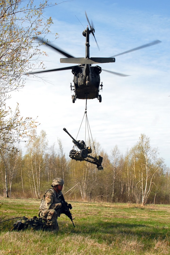 Army Pvt. Harris Saifi provides security as a New York Army National Guard UH-60 Black Hawk helicopter delivers a 105 mm howitzer at Fort Drum, N.Y., to be used during a live-fire exercise, May 4, 2017. Saifi is assigned to the 10th Mountain Division. New York Army National Guard photo by Master Sgt. Raymond Drumsta