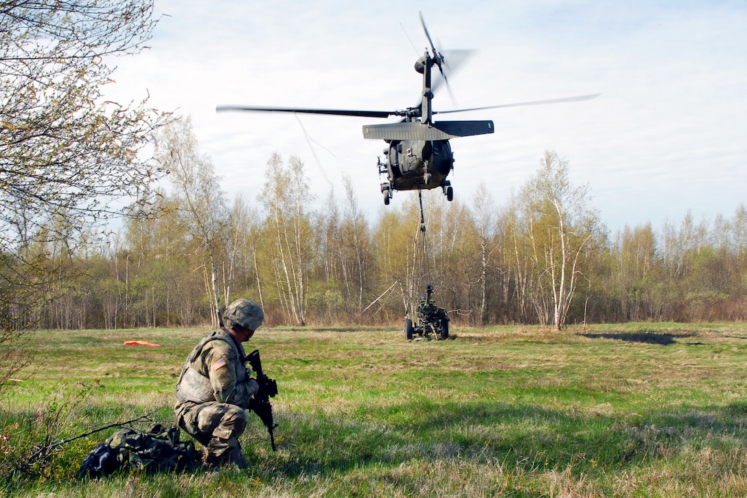 Army Pvt. Harris Saifi provides security as a New York Army National Guard UH-60 Black Hawk helicopter delivers a 105 mm howitzer at Fort Drum, N.Y., to be used during a live-fire exercise, May 4, 2017. Saifi is assigned to the 10th Mountain Division. New York Army National Guard photo by Master Sgt. Raymond Drumsta