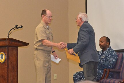 Southeast Regional Maintenance Center’s Commanding Officer, Capt. Dave Gombas (left) shakes hands with Holocaust Survivor Morris Bendit following Gombas’ introduction. Bendit was born in Chernovitz, Ukraine during World War II and was only two months old when his father was forced to enlist into the Russian Army to fight the German Nazis. Four months later, Romanian troops entered Chernovitz. 