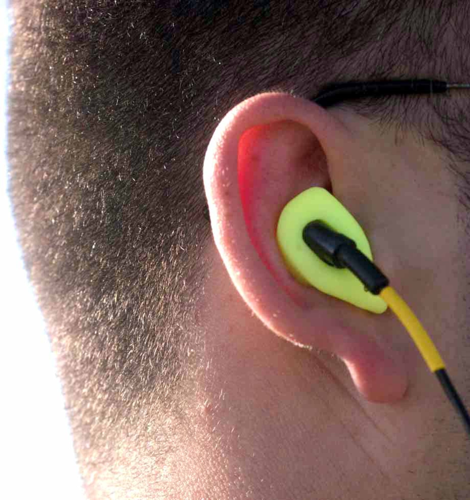 Capt. Kevin Divers of 1st Aerospace Medical Squadron demonstrates the fit of the Atenuating Customized Communications Earpiece System ( A.C.C.E.S.).(U.S. Air Force Photo Illustration/Senior Airman DeLicha E. Germany)