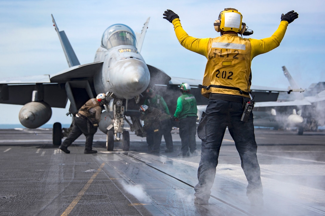A plane director signals the pilot of a Navy F/A-18E Super Hornet as catapult crewmembers prepare the plane for takeoff on the flight deck of the aircraft carrier USS Carl Vinson in the Western Pacific Ocean, May 2, 2017. Navy photo by Petty Officer 2nd Class Sean M. Castellano