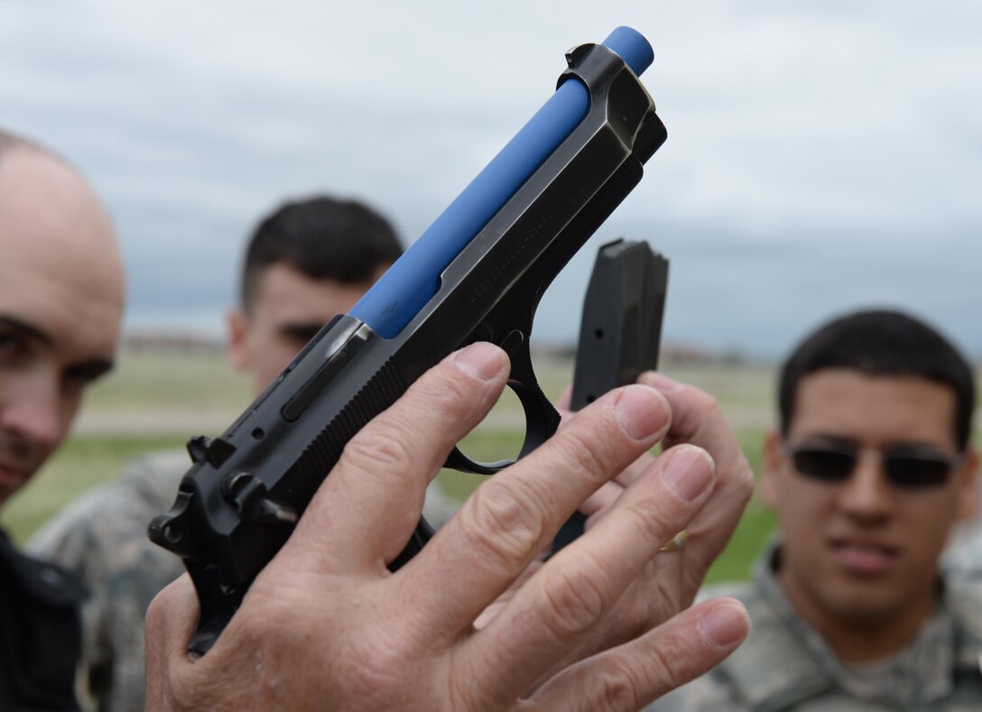 Greg Wooten, the police officer and law enforcement instructor for the 28th Security Forces Squadron, explains the reloading event during a training exercise in at Ellsworth Air Force Base, S.D., May 9, 2017. Airmen simulated an injured support arm, and were required to reload only with their primary firing hand. (U.S. Air Force photo by Airman Nicolas Z. Erwin)