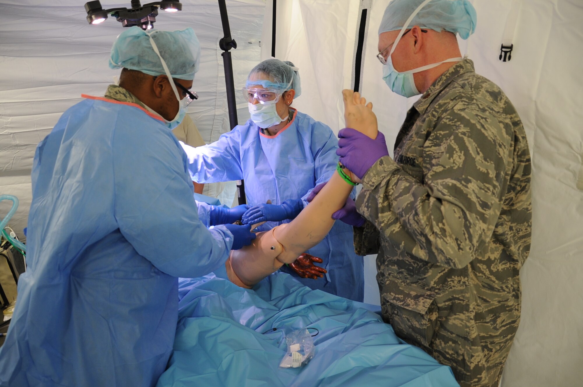 Maj. Jay O'Neill (right), 779th Medical Group operating room nurse, assists positioning a dummy trauma patient for a simulated procedure to bandage a leg wound during Air Force North's validation exercise April 25, 2017 at Camp Atterbury. O'Neil and other Airmen from the 79th Medical Wing, Md., participated in the exercise to be evaluated on the integration and response of their field hospital during a mass casualty scenario. (U.S. Air Force photo by Staff Sgt. Joe Yanik)