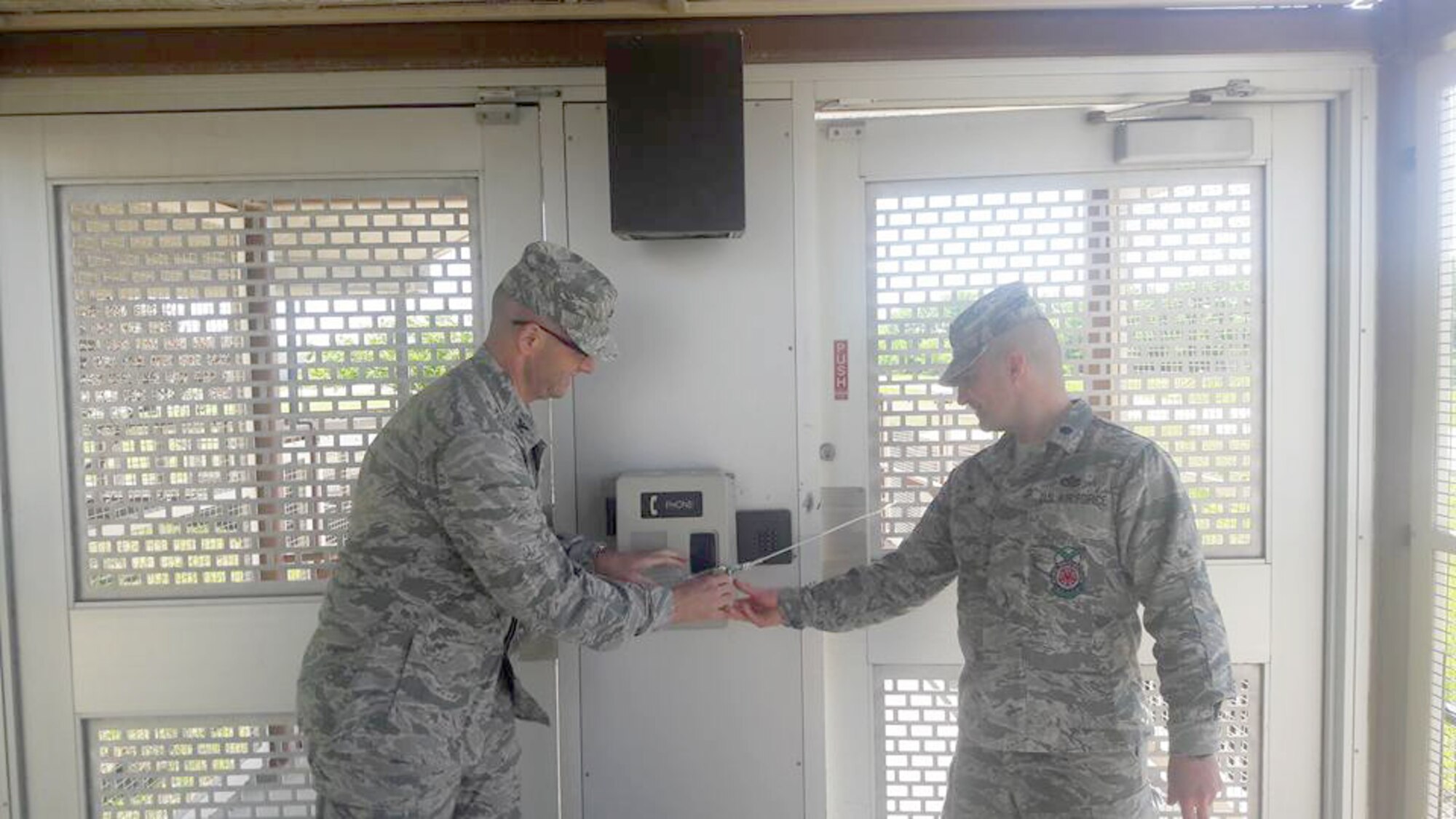 Col. Phil Heseltine, 22nd Air Refueling Wing commander and Lt. Col. Clifford Theony, 22nd Civil Engineer Squadron commander, prepare to unlock the gate to the base pedestrian bridge, May 8, 2017. The bridge was reopened after being closed for two years due to housing construction that rendered the bridge unsafe for traffic. (U.S. Air Force photo/Staff Sgt. Trevor Rhynes)