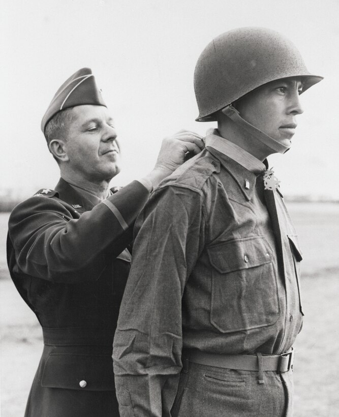 Army 2nd Lt. Ernest Childers, from the Muscogee Creek nation, receives the Medal of Honor from Army Lt. Gen. Jacob L. Devers, at 5th Army headquarters in Italy, April 8, 1944. Childers, operating under heavy enemy fire, wiped out two German machine gun nests near Oliveto, Italy, killing enemy snipers and capturing an artillery observer. This photo is one of 24 panels displayed in the "Patriot Nations" exhibit on the second floor of the National Museum of the American Indian. Photo by Otto Bettmann, courtesy of the National Museum of the American Indian