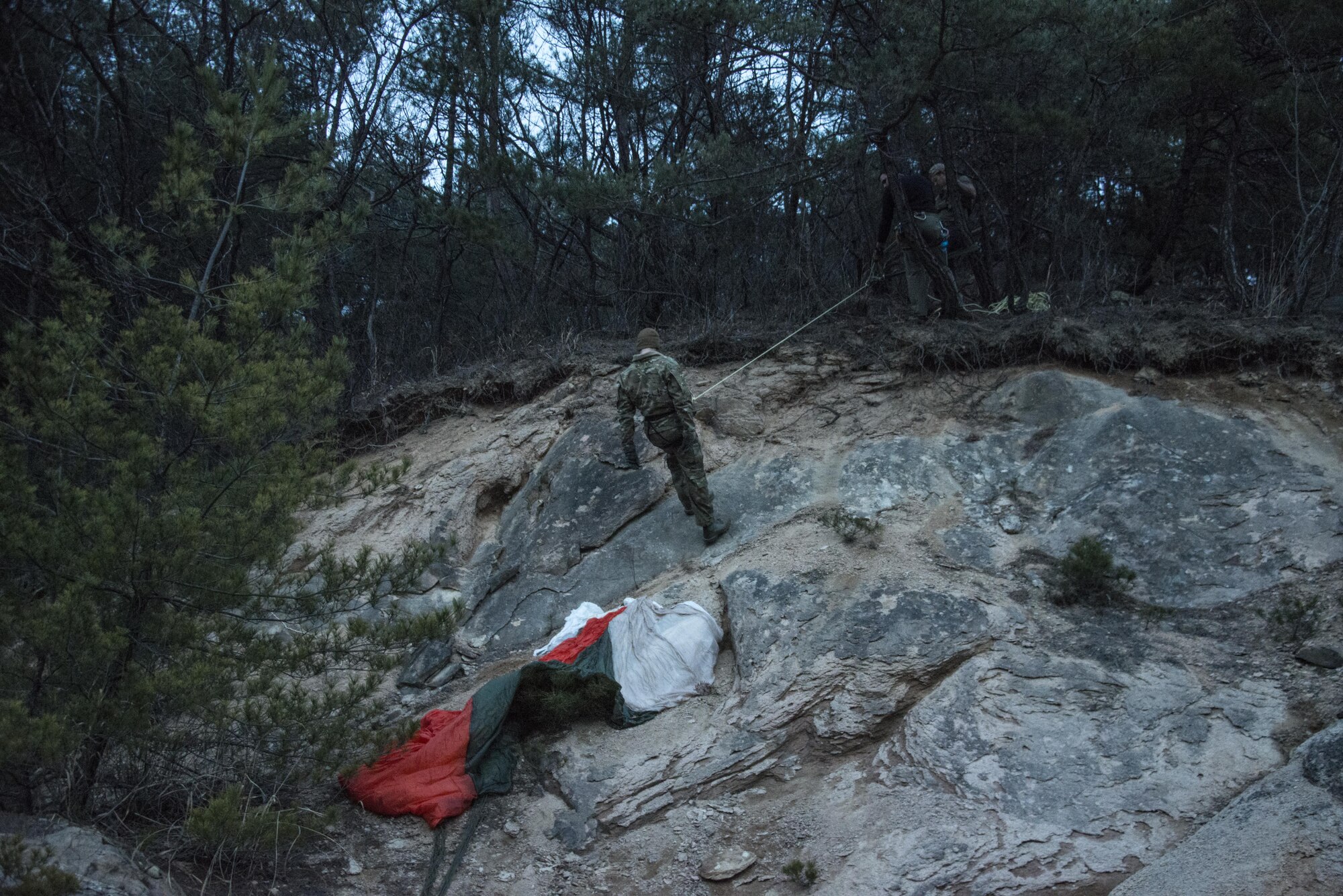 A U.S. Air Force 1st Special Operations Squadron pilot simulates that his parachute got caught in the trees while bailing out of the aircraft, March 30, 2017. In addition to providing survival training to aircrew, the survival, evasion, resistance and escape (SERE) instructors and exercise planners from the 320th Special Tactics Squadron created a complex training mission for the joint personnel recovery team performing the rescue. (U.S. Air Force Capt. Jessica Tait)