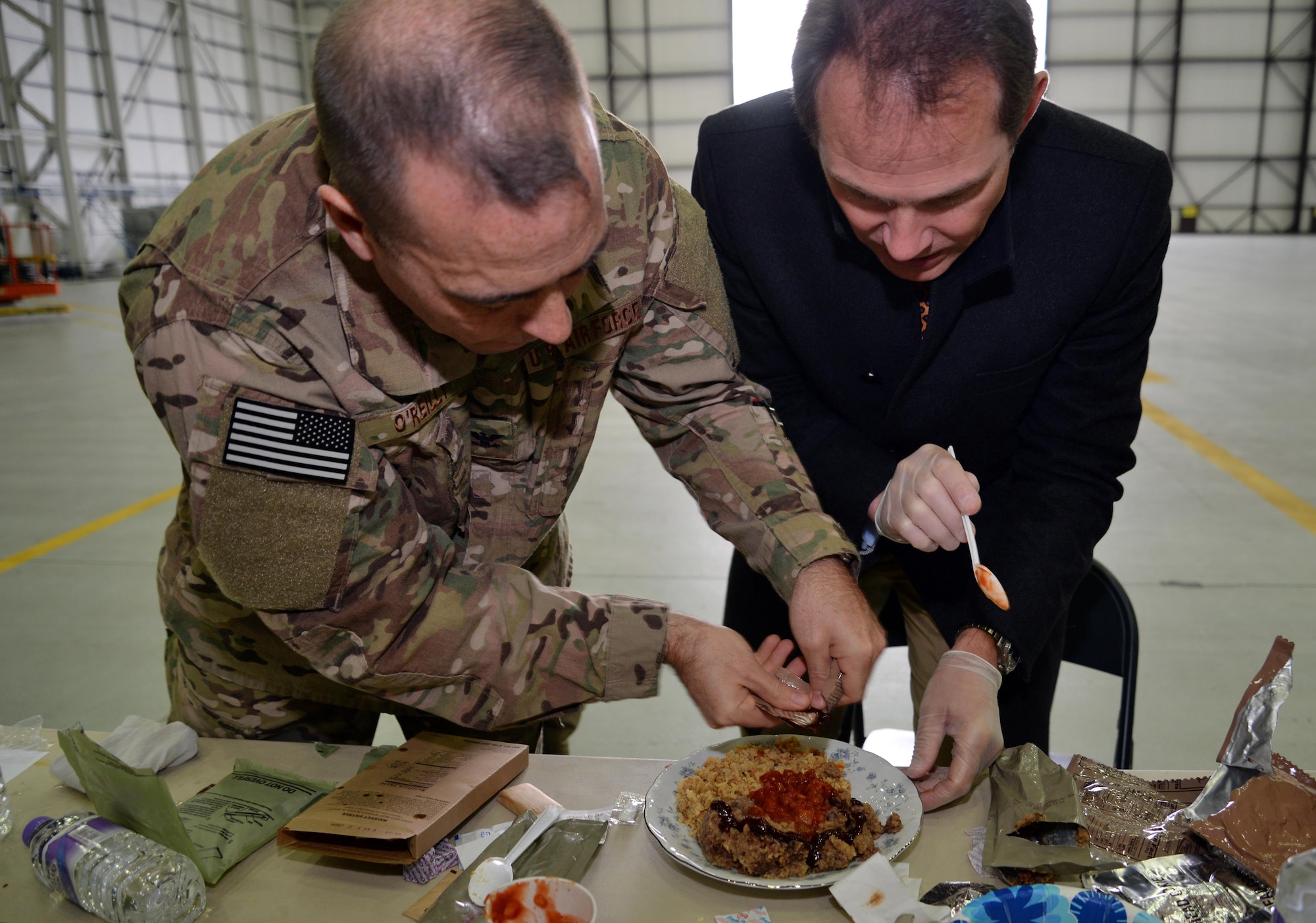 U.S. Air Force Col. Mark O’Reilly, 352nd Special Operations Maintenance Group commander, assists Rob Humphries, 352nd SOMXG honorary commander in creating a gourmet meal for a Meal Ready to Eat Bake-Off Competition for Honorary Commanders’ Day, May 9, 2017, on RAF Mildenhall, England. Base leadership and honorary commander teams create main dishes, side dishes, desserts and drinks with two MREs. (U.S. Air Force photo by Senior Airman Christine Groening)