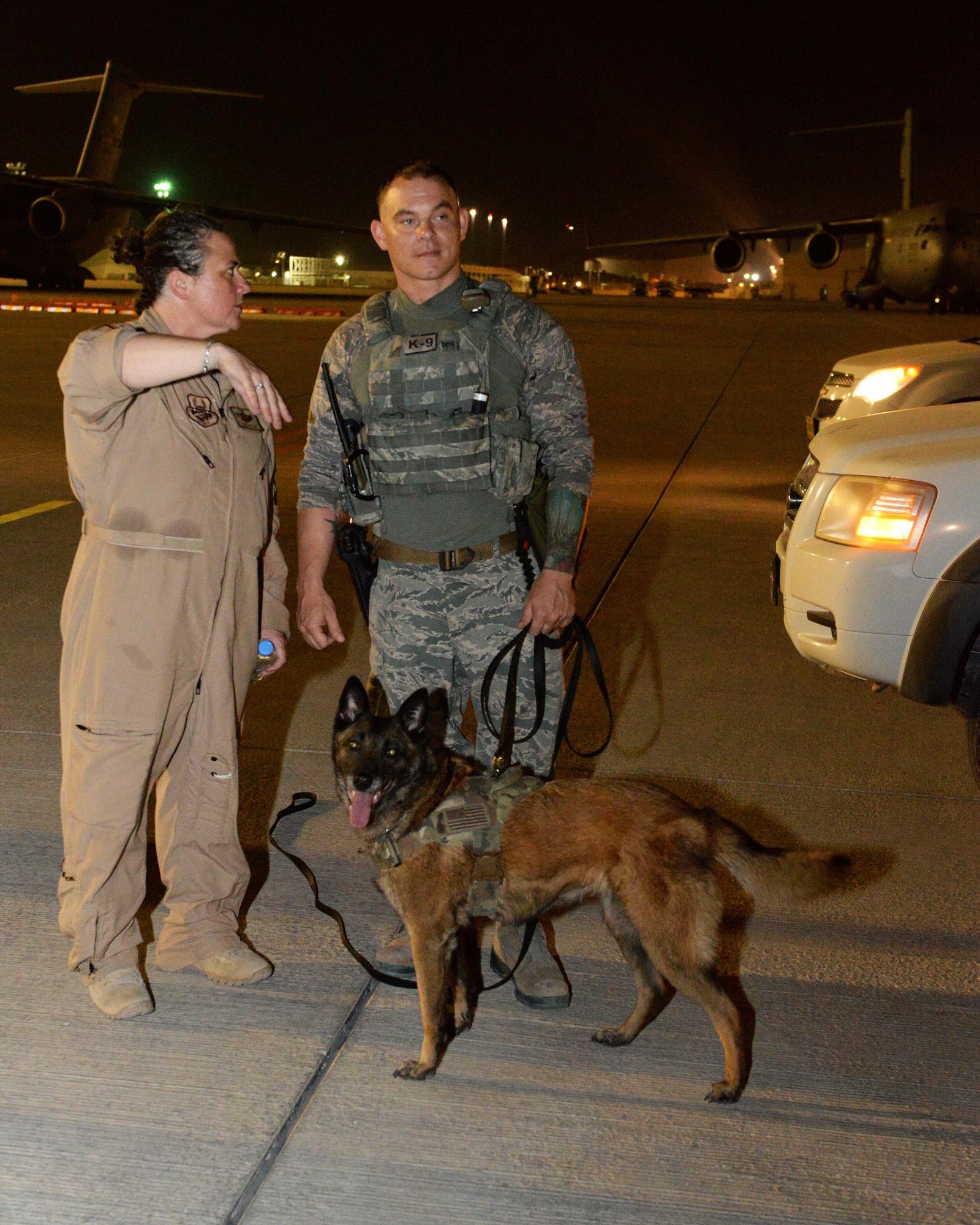 U.S. Air Force Lt. Col. Kara Greene, chief of wing plans and programs with the 379th Air Expeditionary Wing, explains the objective of a detection exercise to Staff Sgt. Christopher Kench, a military working dog handler assigned to the 379th Expeditionary Security Forces Squadron, and his military working dog Beta at Al Udeid Air Base, Qatar, May 4, 2017. Kench and Beta participated in an exercise designed to give the K-9 teams an opportunity to familiarize themselves with the general layout and specific challenges associated with detection aboard an aircraft. (U.S. Air Force photo by Tech. Sgt. Bradly A. Schneider/Released)