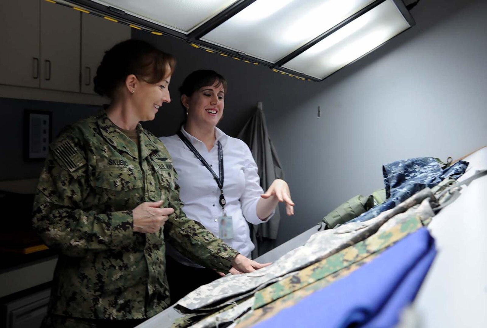 DLA Land and Maritime Commander Navy Rear Adm. Michelle Skubic (left) and Jamie Hieber, director of the Product Test Center Analytical Unit, review uniform materials in a shade lab during Skubics orientation visit.