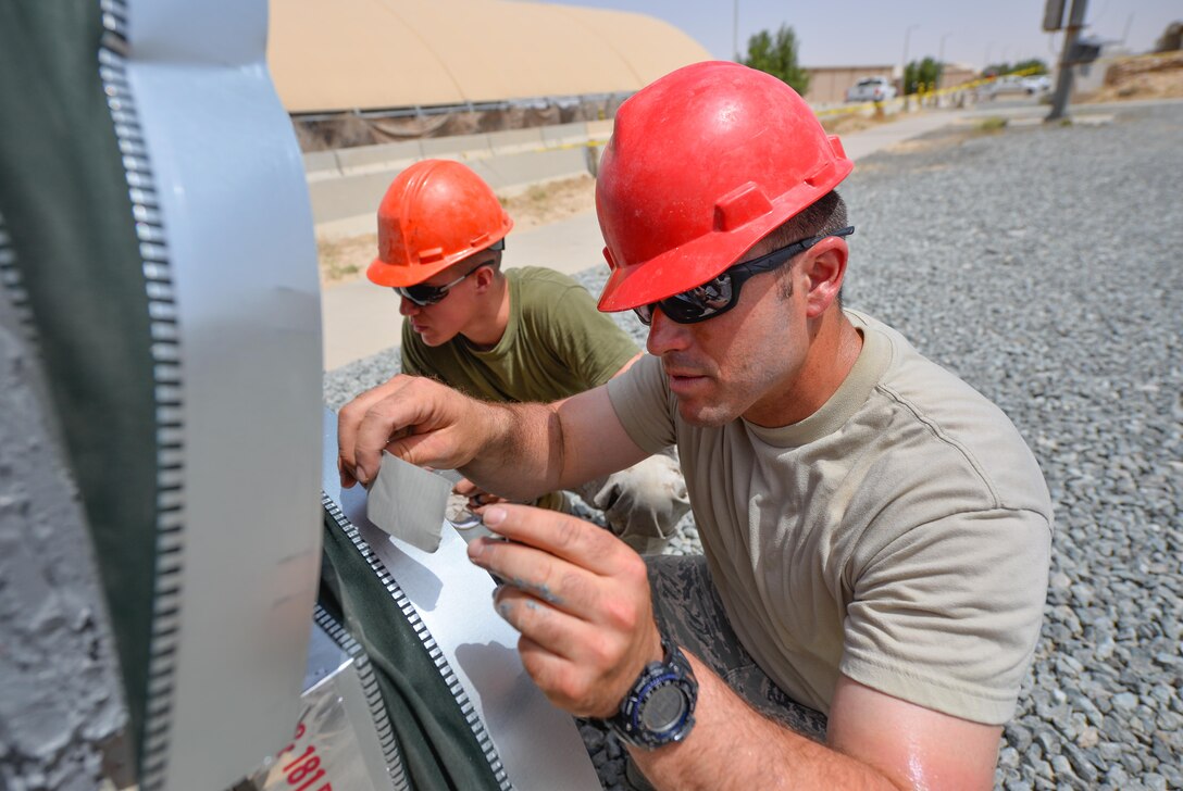 Tech. Sgt. Travis Monks, right, a heating, ventilation and air conditioning technician and NCO in charge of HVAC installs with the 407th Expeditionary Civil Engineer Squadron, works with U.S. Marine Corps Sgt. Jospeh Spore, a welder with Marine Wing Support Squadron 372, to seal air duct connections on an industrial air conditioning unit May 4, 2017, in Southwest Asia. The new cooling system will provide cooled air to an operations building at the 407th Air Expeditionary Group in time for the significant rise of summer temperatures in the region. Marines and Airmen frequently partner to sharpen joint skillsets and complete pressing work assignments. Monks is member of the Air Force Reserve and deployed from March Air Reserve Base, Calif. (U.S. Air Force photo by Staff Sgt. Alexander W. Riedel)