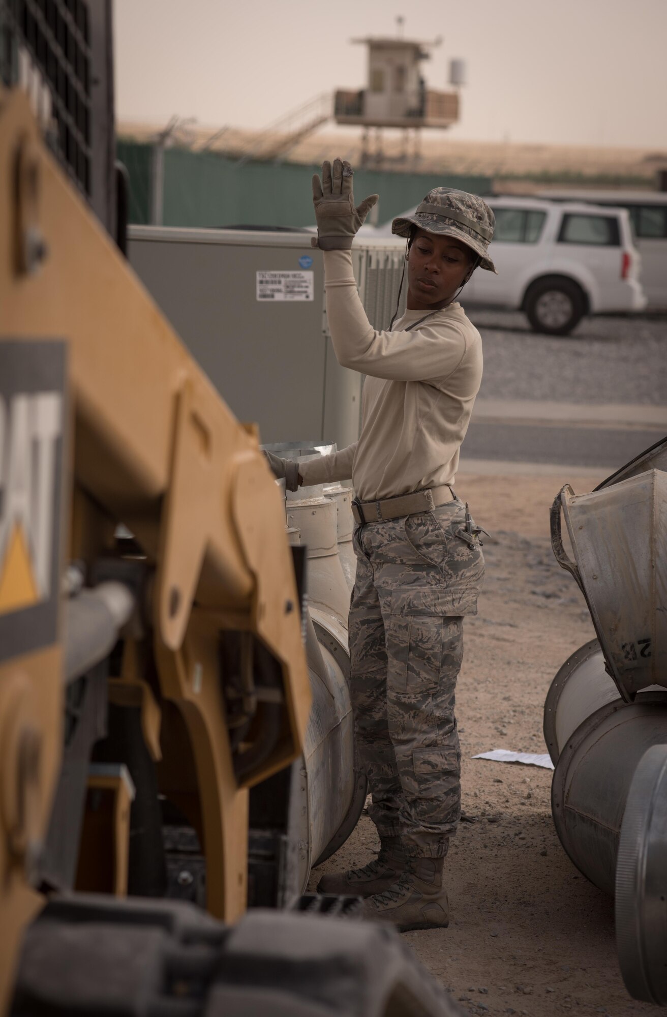 Staff Sgt. Yavita Cotton, a heating, ventilation and air conditioning technician with the 407th Expeditionary Civil Engineer Squadron, guides a compact track loader during the installation of large-diameter air conditioning ducts, May 4, 2017, in Southwest Asia. The new cooling system will provide cooled air to semi-permanent building that will house vital communications equipment supporting missions against ISIS in the Air Force Central Command region of operations. (U.S. Air Force photo by Staff Sgt. Alexander W. Riedel)