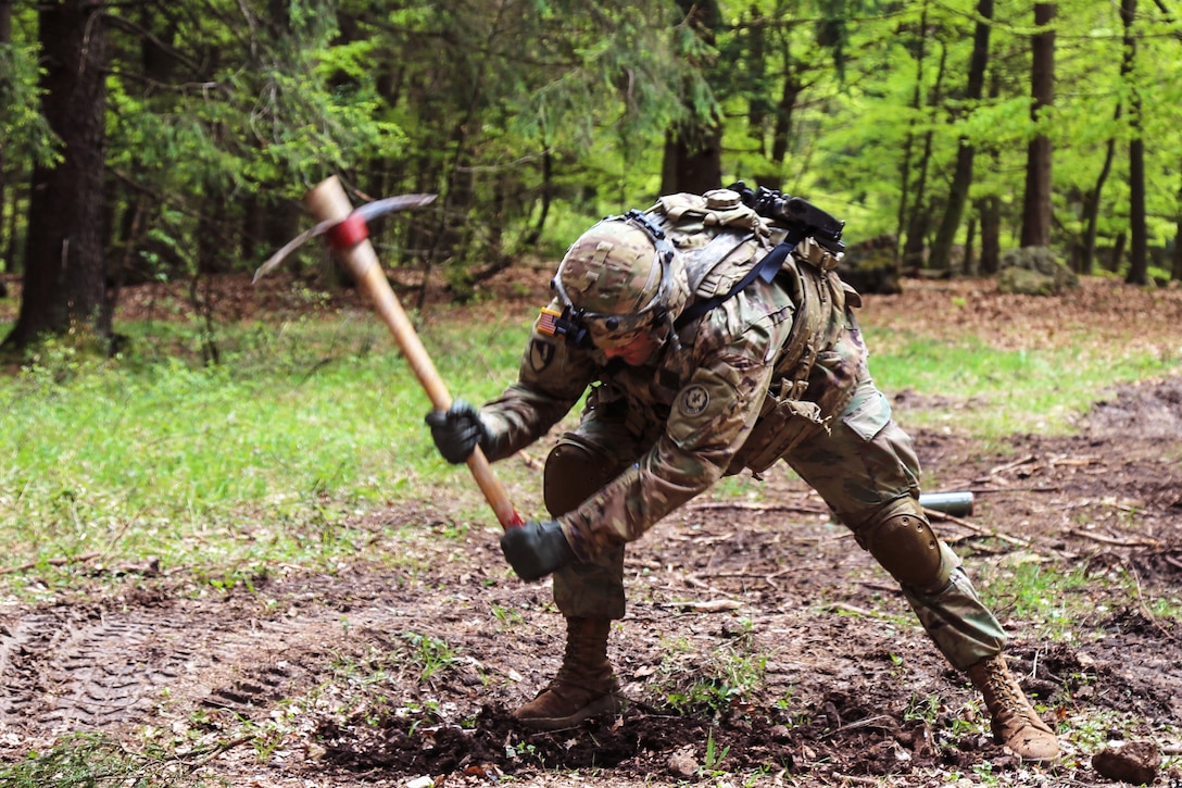 A soldier uses a pickaxe to dig a trench to create an explosive perimeter defense while conducting operations during Saber Junction 17 at the Hohenfels Training Area, Germany, May 7, 2017. Army photo by Sgt. Matthew Hulett