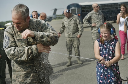 Bella Berg, right, 8 years old, sprays down her father, Chief Master Sgt. Kristopher Berg, left, 437th Airlift Wing command chief, during his final flight at Joint Base Charleston, S.C., May 11, 2017. His wife, Amy, Airmen and civilians were also present to congratulate him during the event. 