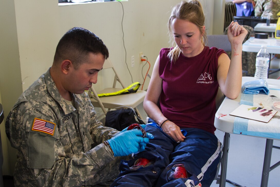 Spc. William Guardiola, a horizontal construction engineer with the 266th Ordnance Company out of Aguadilla, Puerto Rico, creates simulated knee injuries on a civilian role-player as part of the Guardian Response exercise April 29, 2017, at the Muscatatuck Urban Training Center. Nearly 4,100 Soldiers from across the country are participating in Guardian Response 17, a multi-component training exercise to validate U.S. Army units’ ability to support the Defense Support of Civil Authorities (DSCA) in the event of a Chemical, Biological, Radiological, and Nuclear (CBRN) catastrophe. (U.S. Army Reserve photo by Spc. Christopher Hernandez)