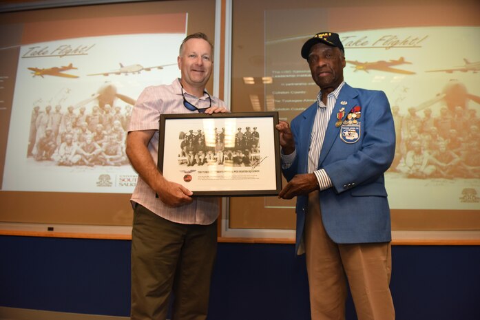 Retired Air Force Col. Rick Williamson, left, a former pilot and squadron commander at Joint Base Charleston, receives a photograph of the Tuskegee Airmen from retired Lt. Col. Enoch “Woody” Woodhouse, right, an original Tuskegee Airman, during a ceremony at the 15th Airlift Squadron auditorium May 11, 2017. Williamson and Woodhouse spoke to attendees of the 2017 Take Flight Aviation Camp and emphasized the importance of education and innovation. The camp is a Science, Technology, Engineering and Mathematics (STEM) program offered to encourage students to be career ready out of high school or college. 