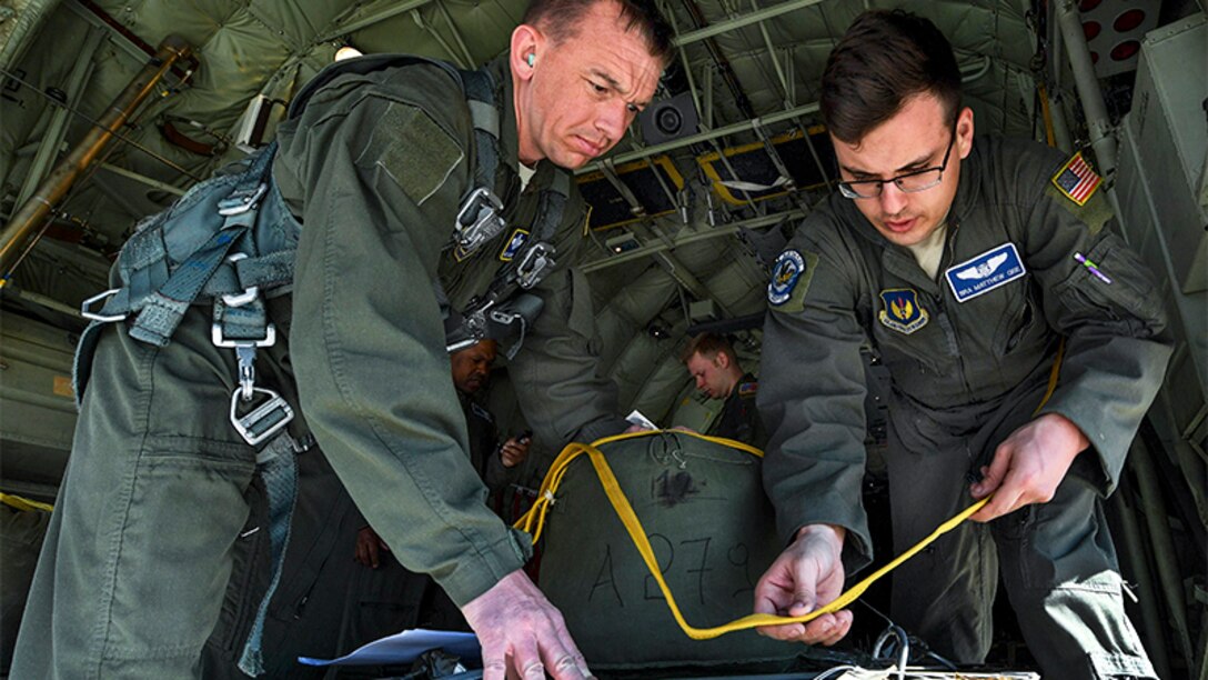 Air Force Senior Airman Matthew Geel, right, prepares cargo for an airdrop while Air Force Master Sgt. CJ Campbell supervises.