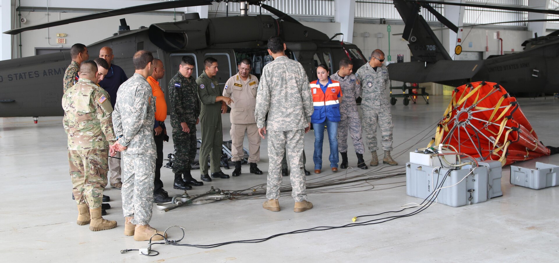 Guard members from Puerto Rico answer questions about helicopter bucket use in forest fires for a visiting delegation from their visitors in the State Partnership Program in San Juan, Puerto Rico.