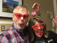 Ken Bauer, 55th Wing Plans, Program and Requirements office international program officer and senior technical advisor with the 55th Wing Plans, Program and Requirements office enjoy heart-shaped sunglasses and treats for Valentine’s Day with Diane Cox, Nebraska Medical Center nurse in Omaha, Nebraska. Bauer, a cancer patient, has used the idea for wearing costumes to chemotherapy to keep fellow patients and staff in good spirits. (Courtesy Photo)
