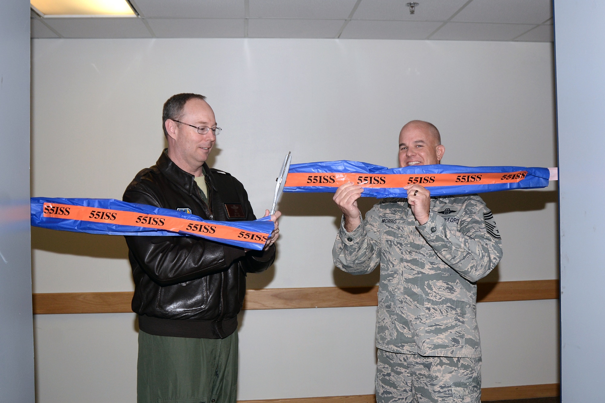 Col. David Berg, 55th Wing vice commander, and Chief Master Sgt. Michael Morris, 55th Wing command chief, cut the ribbon on the 55th Wing Operations Center during a ribbon cutting ceremony at the 55th Intelligence Support Squadron May 1. The WOC is now the central hub for wing-level situational awareness on all of its intelligence, surveillance and reconnaissance assets, as well as its electronic warfare assets, supporting combatant commanders around the world on a daily basis. (U.S. Air Force photo by Kendra Williams)