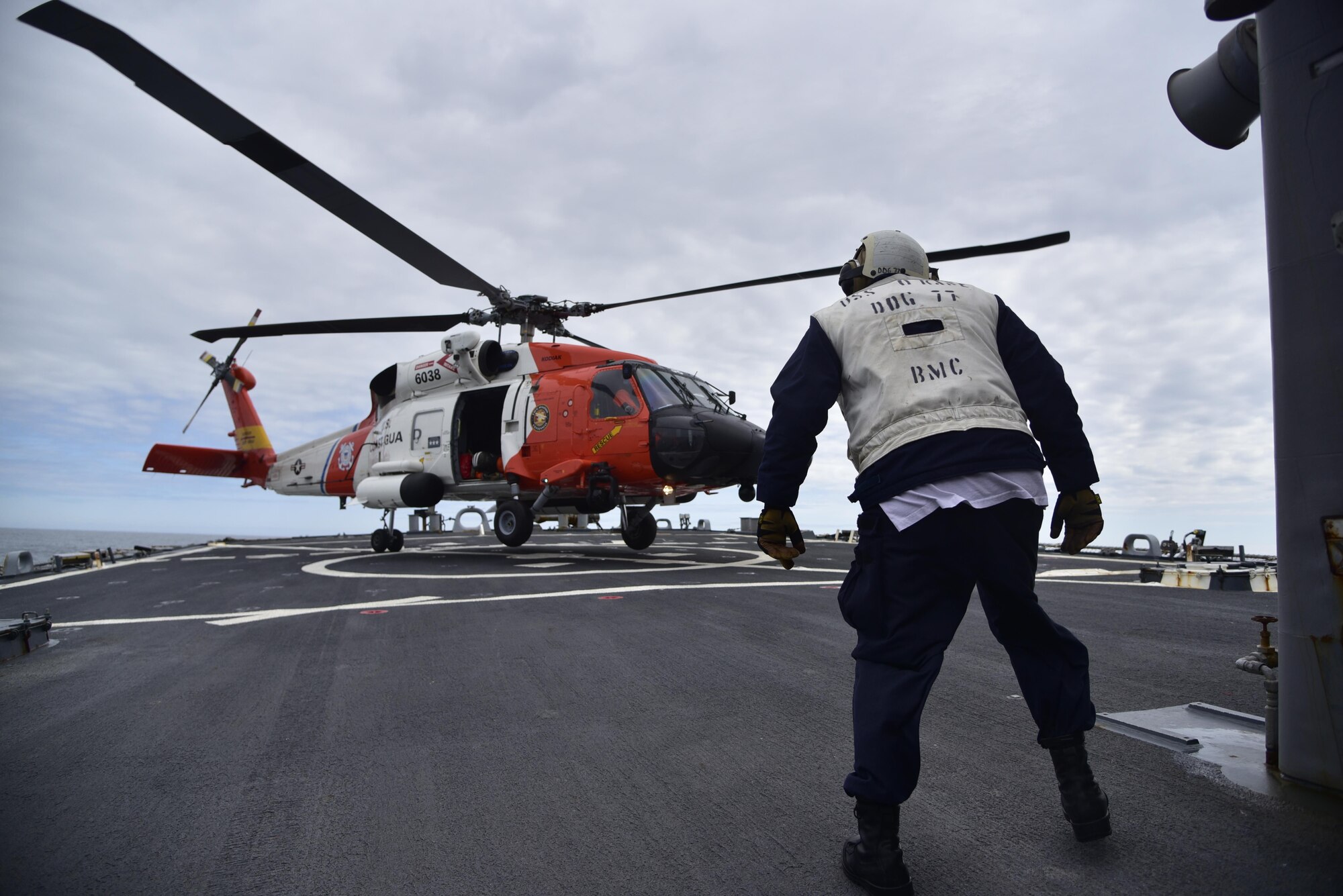 A Chief Boatswain's Mate assigned to Arleigh Burke-class guided missile destroyer USS O'Kane (DDG 77) observes a U.S. Coast Guard MH-60T Jayhawk helicopter assigned to Air Station Kodiak, Alaska, landing during flight deck operations in the Gulf of Alaska. Northern Edge 2017 is Alaska's premiere joint-training exercise designed to practice operations, techniques, and procedures as well as enhance interoperability among the services. Thousands of participants from all the services; Sailors, Soldiers, Airmen, Marines, and Coast Guard personnel from active duty, Reserve and National Guard units, are involved.