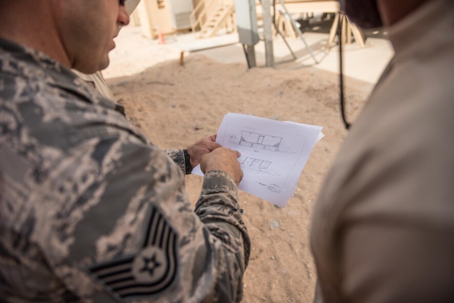 Tech. Sgt. Travis Monks, left, and Senior Airman Jurel Burton, heating, ventilation and air conditioning technicians with the 407th Expeditionary Civil Engineer Squadron, consult a construction plan during the installation of an air conditioning duct, May 4, 2017, in Southwest Asia. The new cooling system will provide cooled air to a crucial computer server that will power operations in the fight against ISIS. (U.S. Air Force photo by Staff Sgt. Alexander W. Riedel)