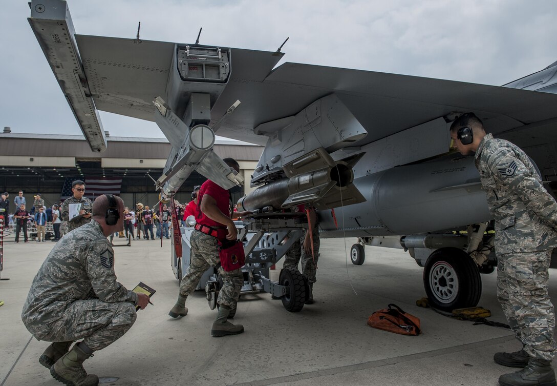 U.S. Air Force Airmen assigned to the 36th Aircraft Maintenance Unit, Osan Air Base, secure a bomb to an F-16 Fighting Falcon while evaluators observed and took notes during the 2017 annual weapons load crew competition on Kunsan Air Base, Republic of Korea, May 13, 2017. This friendly competition tested the capabilities and efficiency of U.S. and ROKAF load crew teams. (U.S. Air Force photo by Senior Airman Colville McFee/Released)  