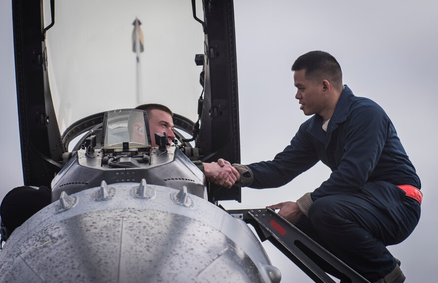U.S. Air Force Capt. Jacob Houder, left, a 13th Fighter Squadron pilot, shakes hands with Airman 1st Class Edwin Chua, right, a 13th FS crew chief, during Northern Edge 2017 at Eielson Air Force Base, Alaska, May 11, 2017. NE17 helped improve 13th FS pilots sharpen their tactical combat skills, to improve command, control and communication relationships, and to develop interoperable plans and programs across the joint force. Both Airmen are stationed at Misawa Air Base, Japan. (U.S. Air Force photo by Tech. Sgt. Araceli Alarcon)