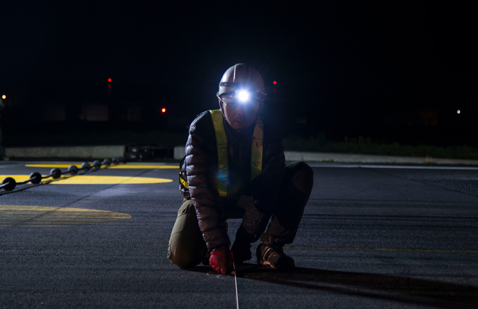 A Japanese contractor with Nippo Corporation holds down a chalk line to make a mark on the runway at Misawa Air Base, Japan, May 5, 2017. More than 50 contracted workers flooded the flightline Wednesday night to tear up the runway, preparing for more than 48,000 feet of flightline to be repaired during a two-month long project. (U.S. Air Force photo by Senior Airman Brittany A. Chase)