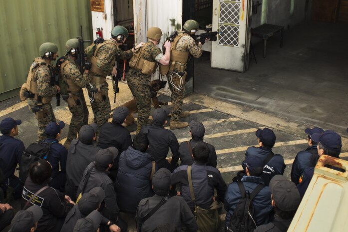 U.S. Marines with the Special Reaction Team (SRT) for Marine Corps Air Station Iwakuni (MCAS), display room-clearing techniques using a military working dog to members of the Hiroshima  and Yamaguchi Prefectural Police Headquarters at MCAS Iwakuni, Japan, March 28, 2017. Members with the Hiroshima and Yamaguchi Prefectural Police Headquarters traveled to the air station to observe SRT conduct high-risk training scenarios. The training ranged from room-clearing, breaching, communication and non-lethal take-down techniques. (U.S. Marine Corps photo by Lance Cpl. Joseph Abrego)