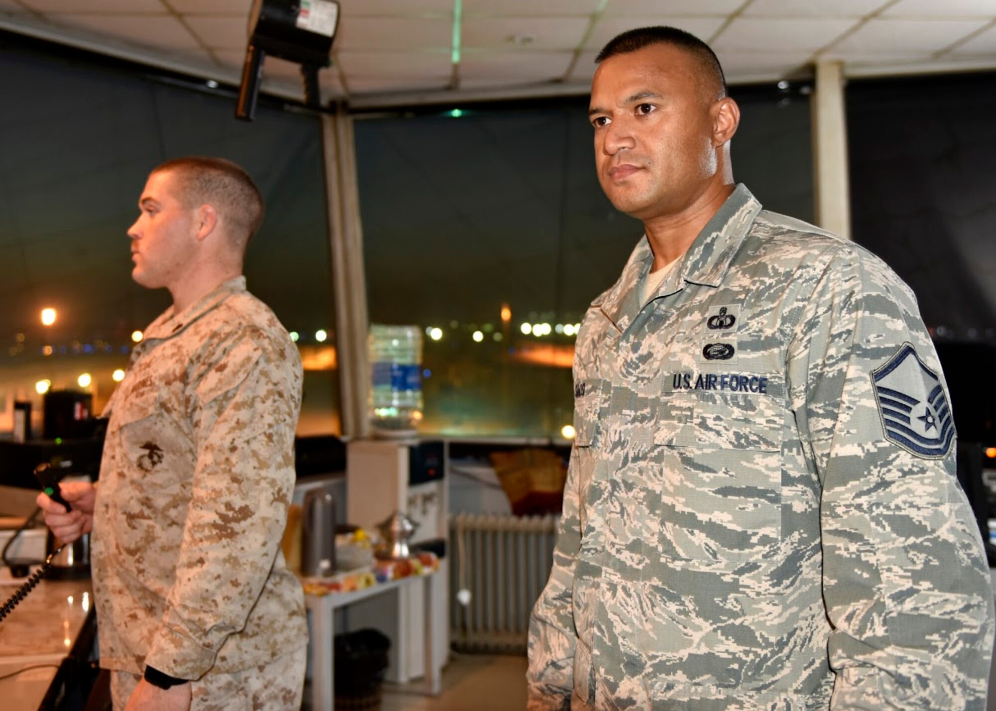 Master Sgt. Stanley Siaosi, 407th Expeditionary Operation Support Squadron air traffic controller, right, observes the airfield as U.S. Marine Corps Sgt. Michael Whelton, Marine Air Control Squadron 1 air traffic controller, instructs a pilot for takeoff May 14, 2017, in outhwest Asia. U.S. air traffic controllers take on a complex role while operating with coalition partners. The international partners have full control over the airfield, while the U.S. controllers focus on safety. (U.S. Air Force photo by Senior Airman Ramon A. Adelan) 