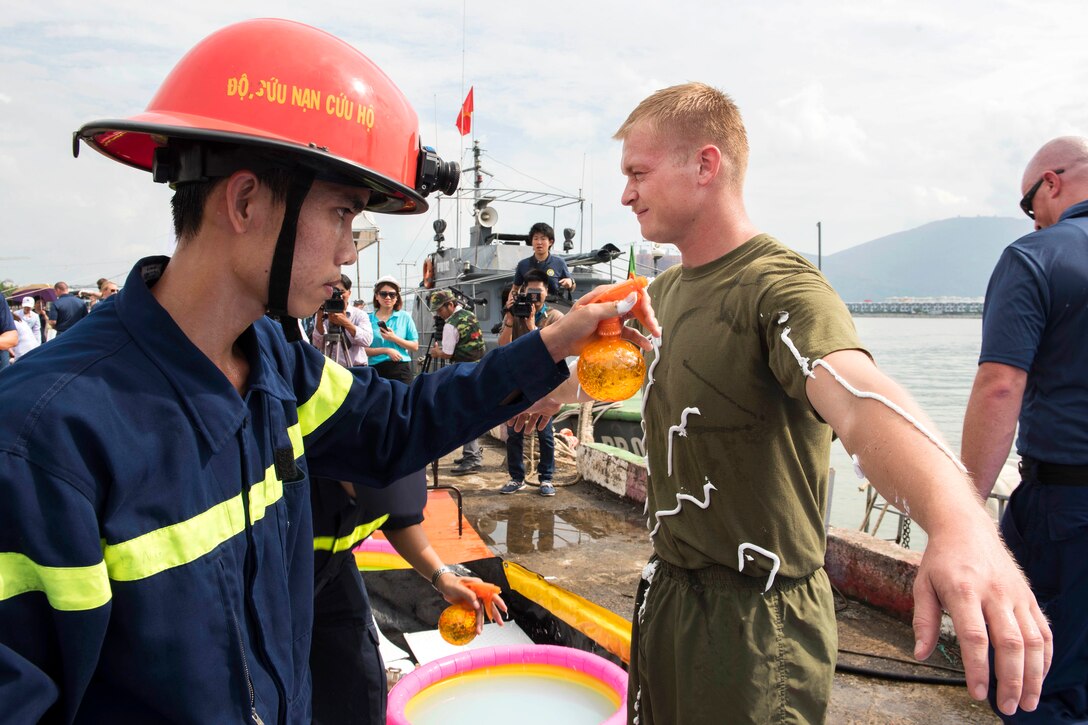 A Vietnamese emergency responder simulates oil contamination removal with Marine Corps Cpl. Spencer Patterson while participating in a search, rescue and oil spill response field training exercise during Pacific Partnership 2017 in Da Nang, Vietnam, May 13, 2017. Patterson is assigned to the 9th Engineer Support Battalion. Navy photo by Petty Officer 2nd Class Joshua Fulton