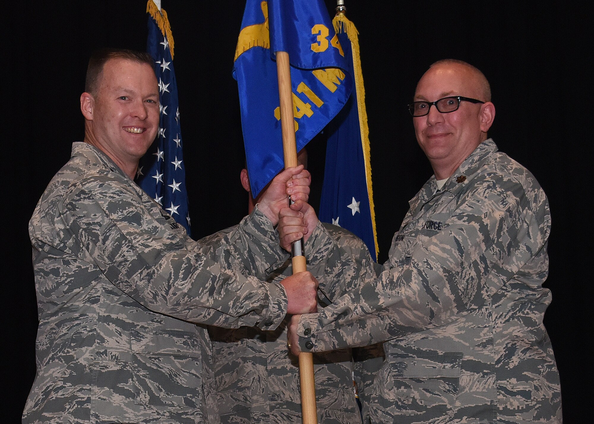 Maj. Joseph Edington, right, accepts command of the 341st Munitions Squadron from Col. Kenneth Speidel, 341st Maintenance Group commander, during an assumption of command ceremony May 12, 2017, at the auditorium at Malmstrom Air Force Base, Mont. (U.S. Air Force photo/Senior Airman Jaeda Tookes)