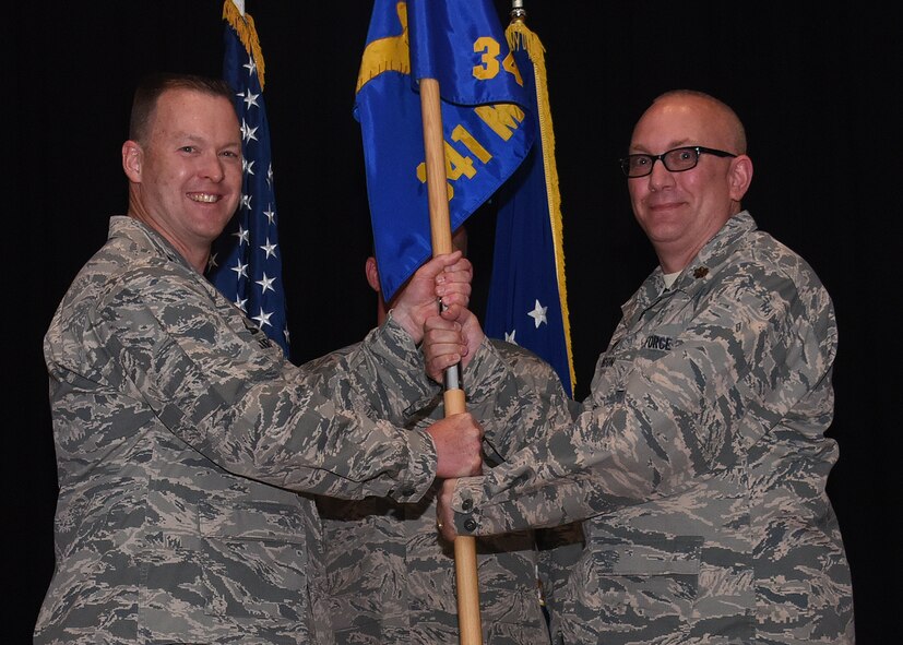 Maj. Joseph Edington, right, accepts command of the 341st Munitions Squadron from Col. Kenneth Speidel, 341st Maintenance Group commander, during an assumption of command ceremony May 12, 2017, at the auditorium at Malmstrom Air Force Base, Mont. (U.S. Air Force photo/Senior Airman Jaeda Tookes)