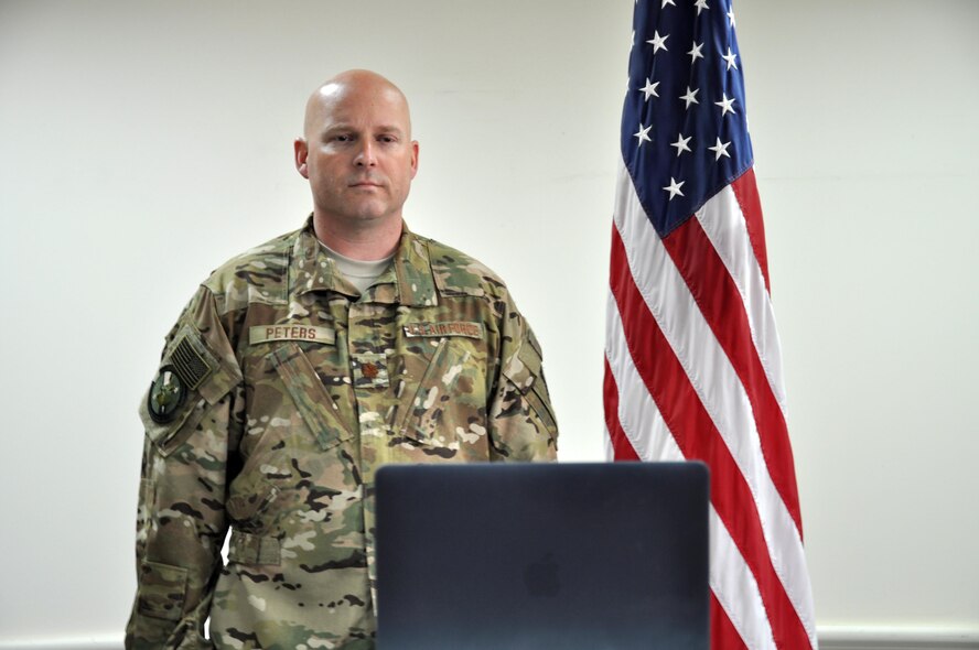 Maj. Bret Peters, the 737th Expeditionary Airlift Squadron assistant director of operations, stands at attention as the Star Spangled Banner plays at his daughter’s commissioning ceremony at the University of North Carolina, May 12, 2017. Peters, a deployed member of the 386th Air Expeditionary Wing, commissioned his daughter via livestream. (U.S. Air Force photo/Master Sgt. Eric Sharman)