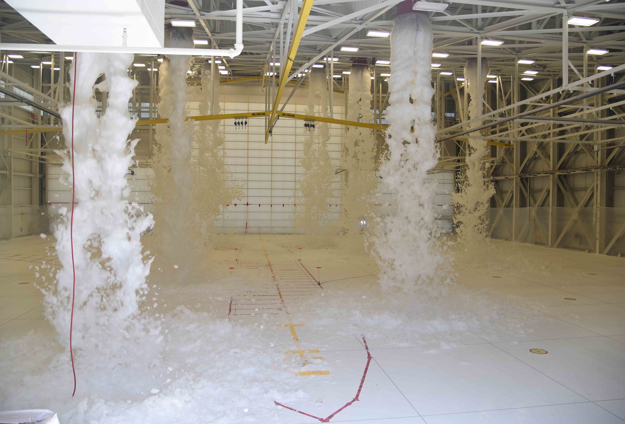 Foam from a fire suppression system covers an outline of a KC-46 Pegasus during a test May 12, 2017 at McConnell Air Force Base, Kan. To pass inspection, the foam must cover 90% of the aircraft within 60 seconds and a meter of the entire building within four minutes. (U.S. Air Force photo/Airman 1st Class Erin McClellan)