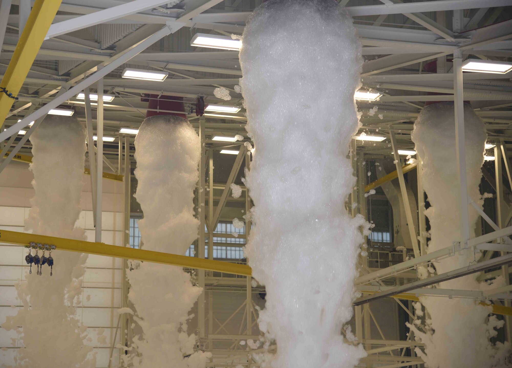 Foam from a fire suppression system pours from generators on the ceiling of a KC-46 Pegasus hangar May 12, 2017 at McConnell Air Force Base, Kan. A test was performed in the three-bay hangar as part of the final inspections to the building. (U.S. Air Force photo/Airman 1st Class Erin McClellan)