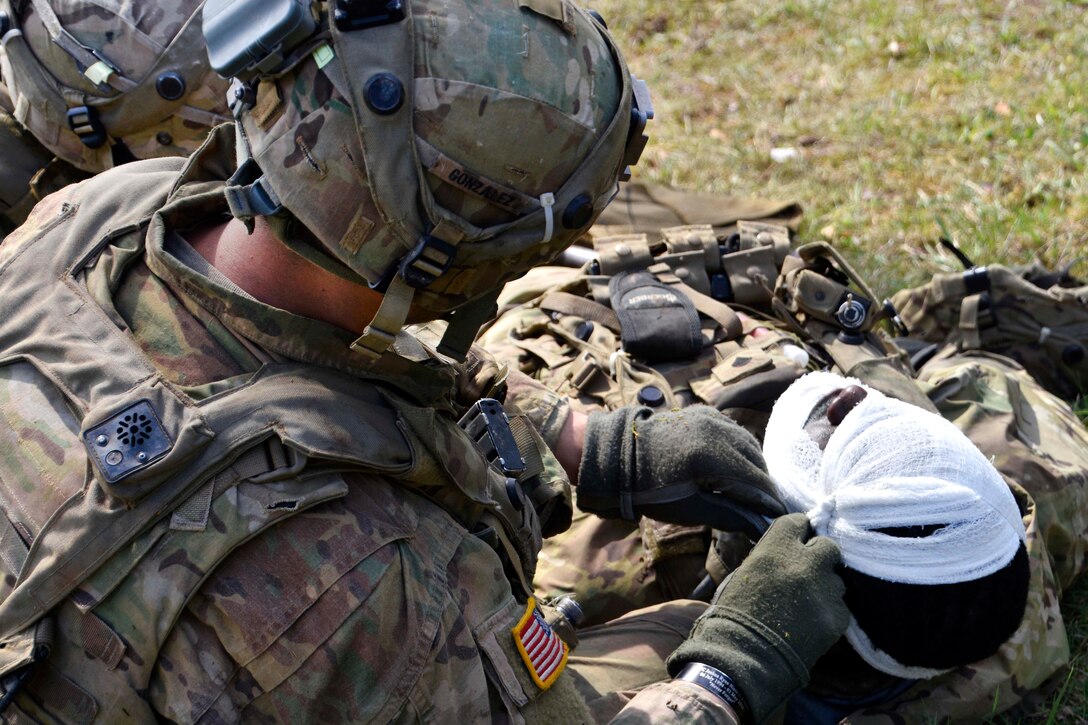 A soldier applies a head bandage to a mock casualty while conducting land operations during Saber Junction 17 at the Hohenfels Training Area, Germany, May 6, 2017. Army photo by Sgt. Devon Bistarkey