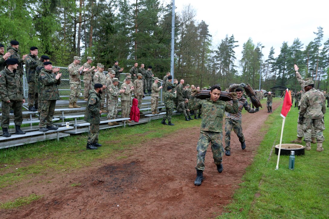 German soldiers compete against other nations in a relay race with tank-related objects while U.S. soldiers cheer them on in Grafenwoehr, Germany, May 12, 2017. Army photo by Staff Sgt. Kathleen V. Polanco