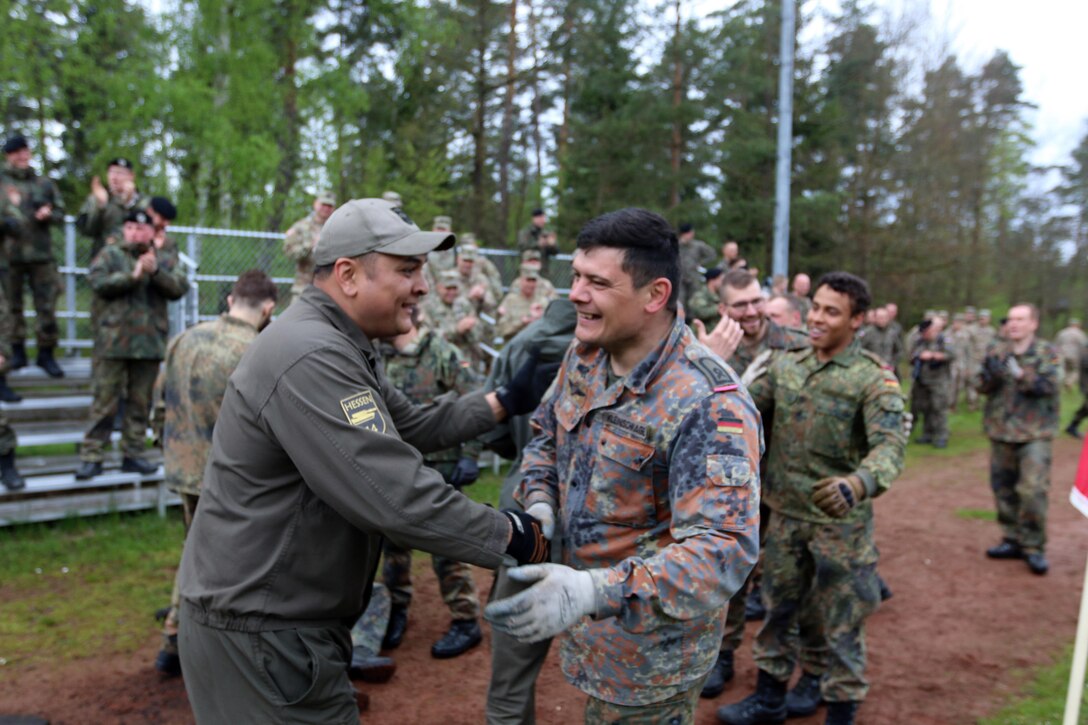 An Austrian soldier congratulates a German soldier upon completion of a relay race with tank-related objects while U.S. soldiers cheer them on in Grafenwoehr, Germany, May 12, 2017. The Strong Europe Tank Challenge is co-hosted by U.S. Army Europe and the German army, May 7-12, 2017. Army photo by Staff Sgt. Kathleen V. Polanco