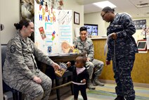 Teziah Davis, 1-year-old, grabs a sticker and crayon from Master Sgt. Tiffany Griego, while her mother, Petty Officer 3rd Class Otisa Williams, with Strategic Communications Wing ONE, and Staff Sgt. Alan Nham, look on. Master Sgt. Griego and Staff Sgt. Nham, both with the 72nd Aerospace Medicine Squadron, handed out goodies and educational materials at the Child Development Center West on April 5 during Public Health Week. (Air Force photo by Kelly White)