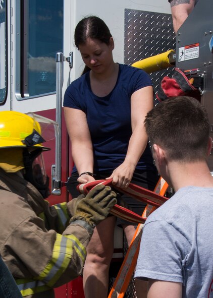 Airman 1st Class Colleen Erickson, 119th Wing firefighter from the North Dakota Air National Guard based in Fargo, N.D., hands a hose to a Post #9463 Fire Explorer from Minot, at Minot Air Force Base, April 30, 2017. The Minot Boy Scouts of America and Fire Explorers learned about the fast-paced response required to fight fires. (U.S. Air Force photo/Airman 1st Class Alyssa M. Akers)