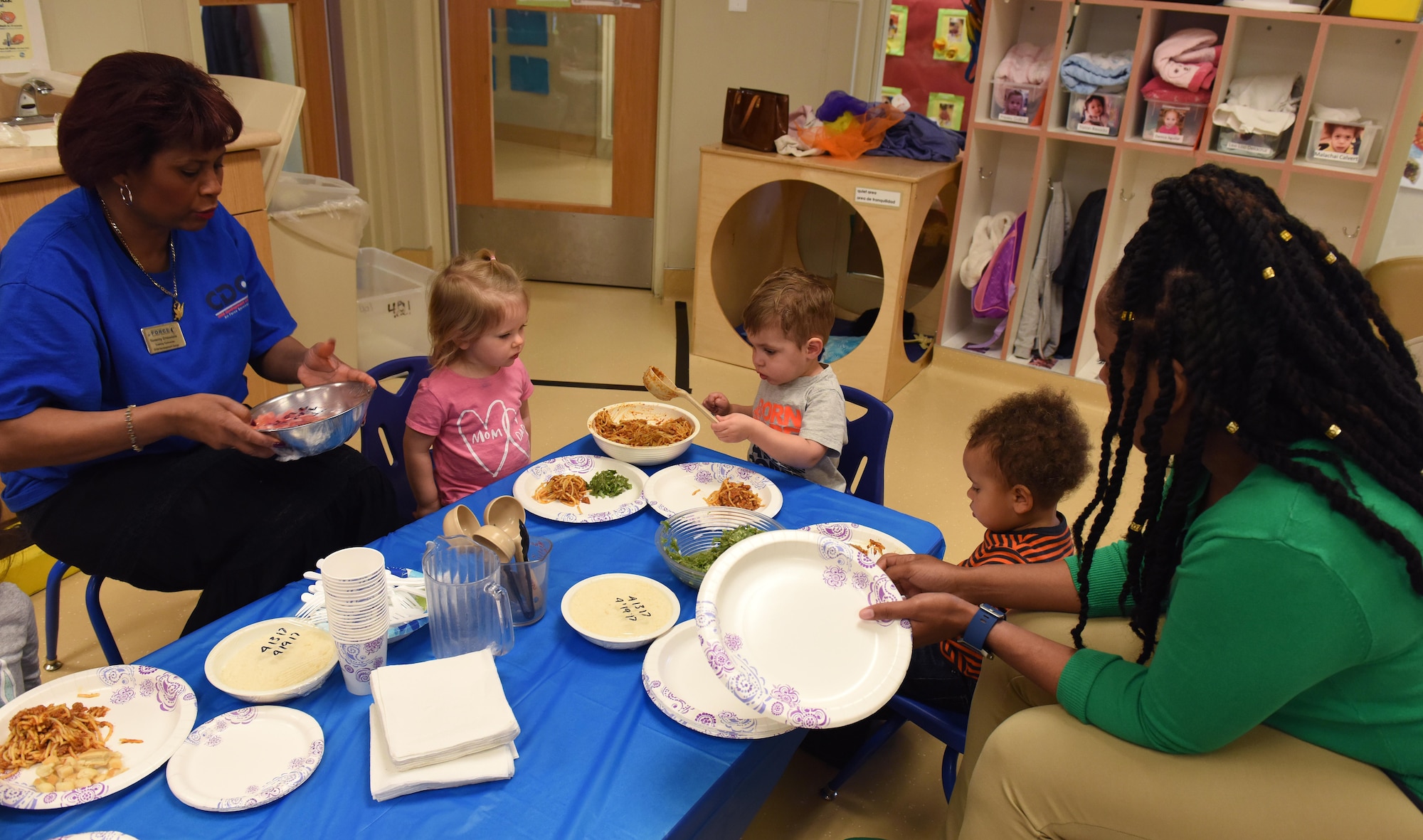 Two 9th Force Support Squadron child development center staff help care for a group of children during a spaghetti luncheon April 14, 2017, at Beale Air Force Base, California. When a recent hiring freeze came down, Beale’s CDC experienced some staffing issues, but they were still able to provide child care with creative problem solving and help from their leadership. (U.S. Air Force photo/Chandresh Bhakta)