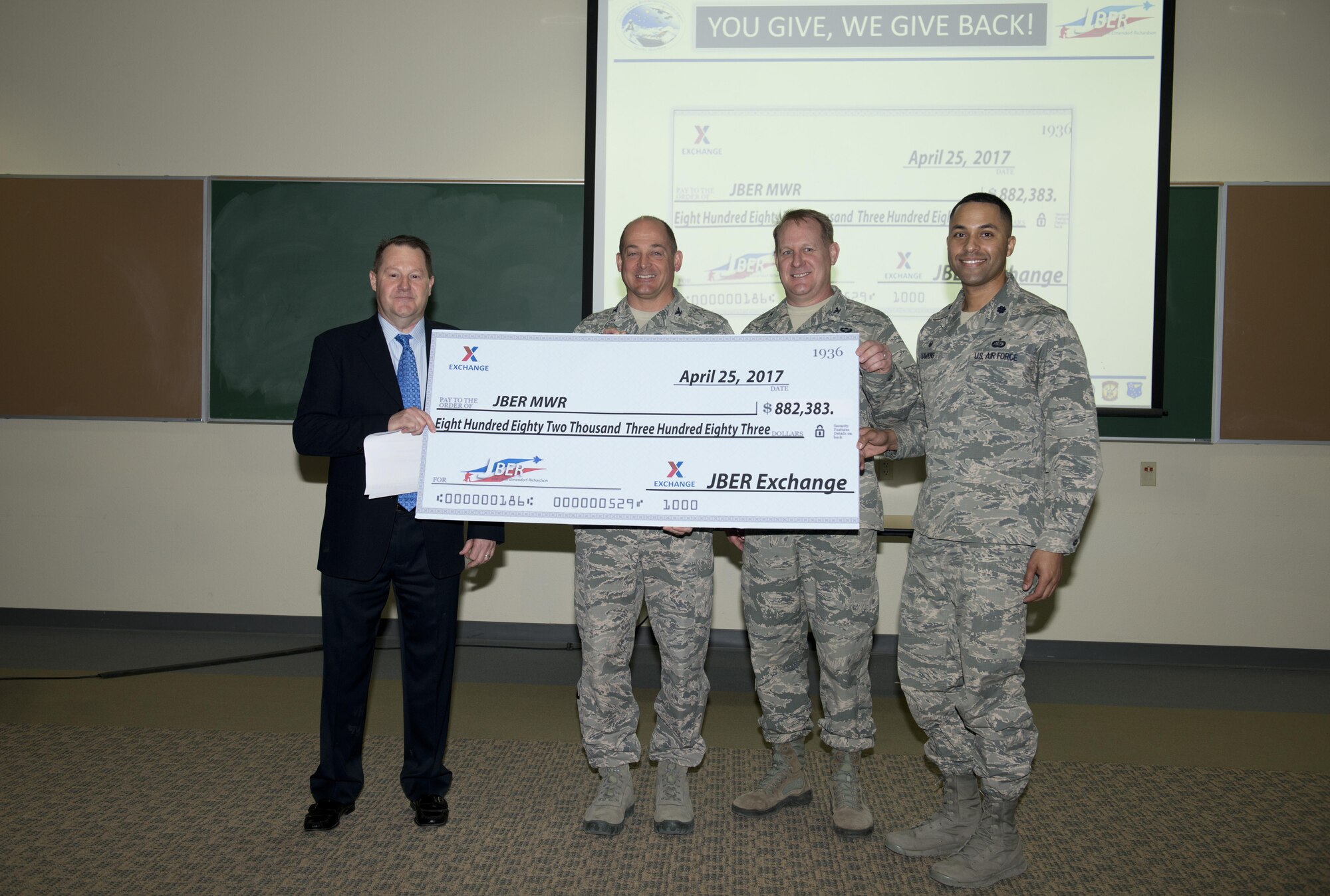 Ray Stewart III, the general manager for the Southern Alaska Exchange presents Air Force Col. George T.M. Dietrich III, 673d Air Base Wing and Joint Base Elmendorf-Richardson, Alaska commander, a check for $882,383 at the community action council, May 11. The funds were given throughout the course of a year in monthly dividends to the Morale, Welfare and Recreation department here.