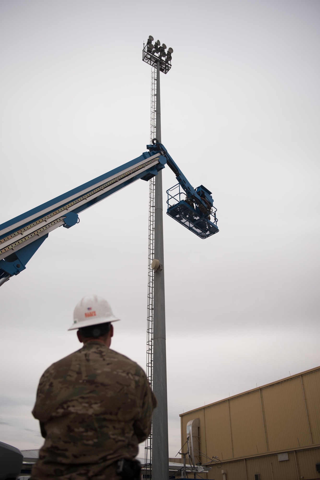 Staff Sgt. Mark Cox, a 455th Expeditionary Civil Engineer Squadron electrical systems craftsman, observes as a boom lift rises at Bagram Airfield, Afghanistan, May 12, 2017. Electrical systems Airmen are responsible for installing, repairing and maintaining electrical networks, ensuring that the primary source of energy for an installation is always available. (U.S. Air Force photo by Staff Sgt. Benjamin Gonsier)
