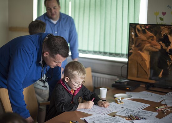 A U.S. Air Commando assigned to the 352d Special Operations Wing assists his son in an activity during Roald Dahl day at the Preservation of the Force and Family building May 13, 2017 on RAF Mildenhall, England. The aim of the day was to recognize the work of Roald Dahl, a celebrated children's author and Word War II Royal Air Force fighter with ties to Mildenhall, and promote resiliency through the bonding of parents reading to their children. (U.S. Air Force photo by Capt Chris Sullivan)